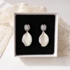 Boucles d'oreilles STELLA argentées dans leur écrin : pétale de porcelaine froide blanc sous une puce plaqué platine sertie de zircones, by Marguerite
