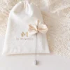 Boutonnière VIVIENNE posée sur son pochon en lin, pétales nacrés en porcelaine froide et épingle argentée, by Marguerite