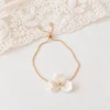 Bracelet NINA posé près d’une dentelle : chaîne dorée réglable, curseur et petits zirconiums aux extrémités, by Marguerite