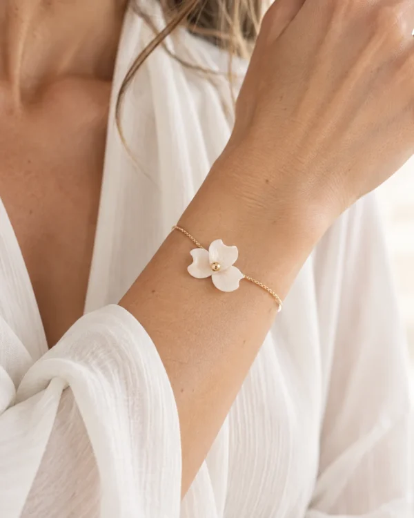 Bracelet NINA porté au poignet avec une chemise blanche en gaze, fleur de porcelaine froide et perle dorée, by Marguerite