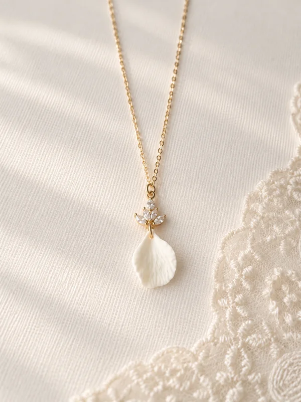 Accueil 13 Collier NOÉMIE : chaîne dorée, puce fleur à cristaux et pétale de porcelaine froide, posé sur un tissu clair et de la dentelle, by Marguerite
