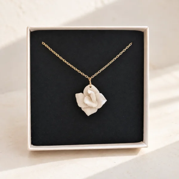 Collier APOLLINE doré présenté dans son écrin : fleur blanche en porcelaine froide sur un velours noir, by Marguerite