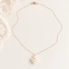 Collier APOLLINE en entier : chaîne fine dorée, fermoir mousqueton et fleur de porcelaine, près d'une dentelle, by Marguerite