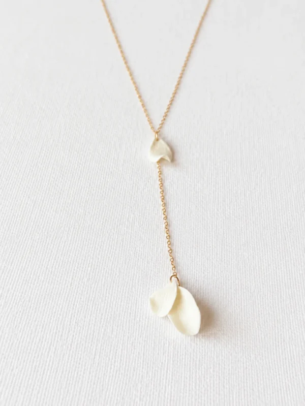 Collier de dos DIANE 9 Une perle ronde à l'avant, et dans le dos trois petits pétales de porcelaine qui bougent au moindre pas : DIANE est un collier de dos de mariage aux pétales de porcelaine, léger et délicat. Sa chaîne fine dessine une ligne de lumière le long d'une robe dos nu, du jour J aux soirées d'été. <ul> <li>Fait main au Pays basque, en France</li> <li>Chaîne gold filled 14 carats, perle de culture, pétales en porcelaine froide</li> <li>Longueur 65 ou 70 cm, pendant de 10 cm · sur mesure possible</li> </ul> Collier de dos DIANE : deux petits pétales de porcelaine froide superposés au bout de la chaîne gold filled, by Marguerite