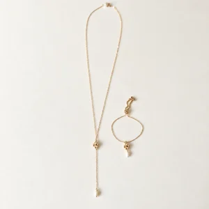 Collier de dos EMMA et bracelet EMMA posés côte à côte : même petite fleur dorée et perles d'eau douce, by Marguerite