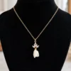 Collier KATE sur un buste noir : fine chaîne gold filled, pendentif de cristaux et bouton de fleur en porcelaine blanche, by Marguerite
