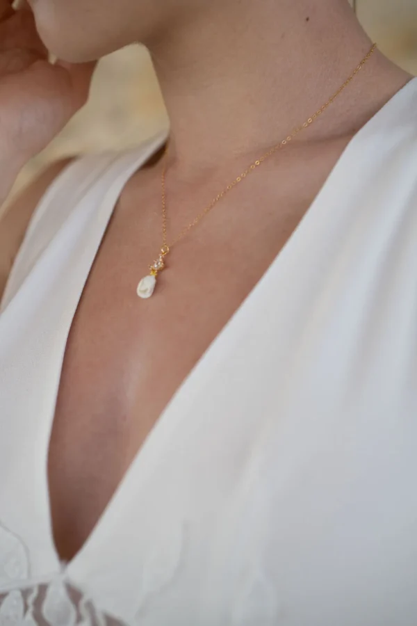 Collier KATE porté avec une robe blanche à décolleté en V : petit bouton de fleur en porcelaine et cristaux sur chaîne dorée, by Marguerite