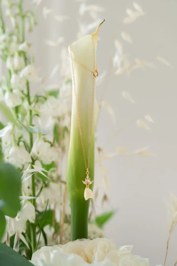 Collier KATE suspendu à un arum blanc, entouré de fleurs blanches et de graminées : chaîne dorée et bouton de fleur en porcelaine, by Marguerite