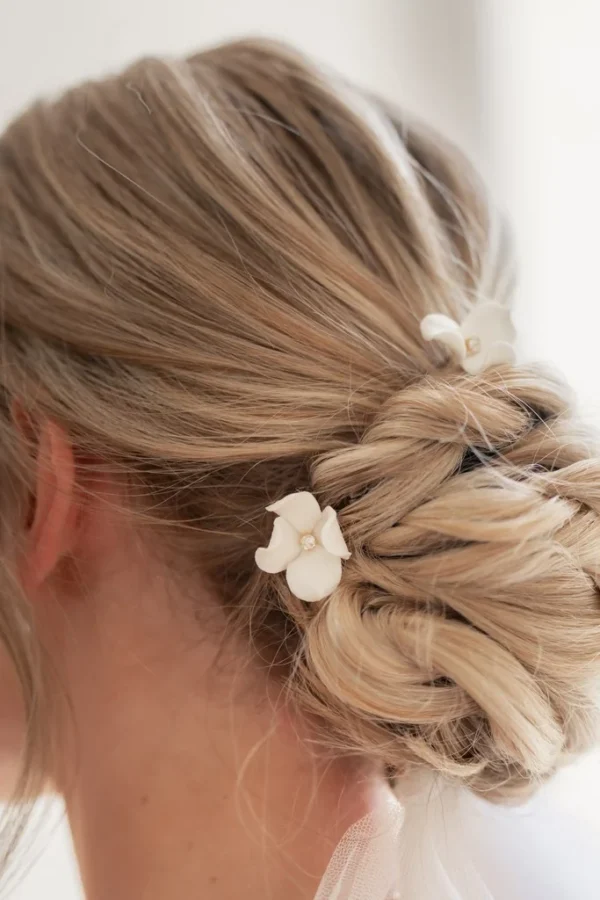Épingles PAULINE 2 <p>Une petite fleur de porcelaine froide à peine éclose par épingle, chacune différente, de 1,5 à 3 cm, autour d’un strass : PAULINE, ce sont des épingles à chignon de mariée que vous choisissez à l’unité, de deux à sept. Je compose l’assortiment en mêlant les tailles, pour que les fleurs s’accordent comme un petit bouquet dans votre coiffure.</p><ul><li>Fait main au Pays basque, en France</li><li>Fleurs en porcelaine froide, cœur en strass, épingles en U de 7 cm</li><li>De 2 à 7 épingles · version dorée ou argentée</li></ul> Chignon de mariée tressé orné de deux épingles PAULINE, petites fleurs blanches en porcelaine, by Marguerite