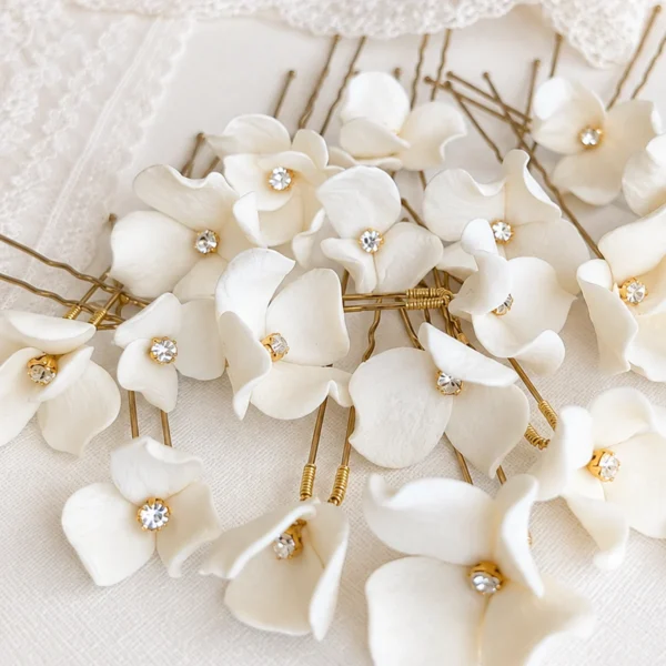 Épingles PAULINE 1 <p>Une petite fleur de porcelaine froide à peine éclose par épingle, chacune différente, de 1,5 à 3 cm, autour d’un strass : PAULINE, ce sont des épingles à chignon de mariée que vous choisissez à l’unité, de deux à sept. Je compose l’assortiment en mêlant les tailles, pour que les fleurs s’accordent comme un petit bouquet dans votre coiffure.</p><ul><li>Fait main au Pays basque, en France</li><li>Fleurs en porcelaine froide, cœur en strass, épingles en U de 7 cm</li><li>De 2 à 7 épingles · version dorée ou argentée</li></ul> Épingles à chignon PAULINE : fleurs blanches en porcelaine froide de tailles variées, cœur en strass, by Marguerite