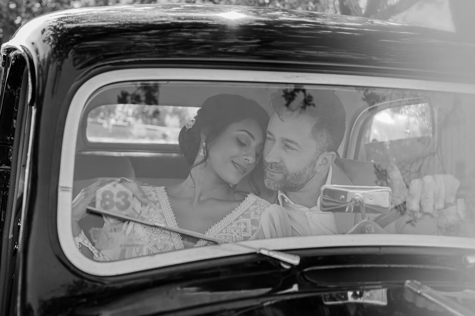 Couple de mariés tendrement enlacés dans une voiture ancienne, photo en noir et blanc, by Marguerite