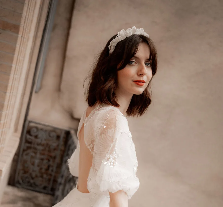 Accueil 2 Mariée aux cheveux courts sur un balcon en fer forgé, robe brodée dos nu, portant la couronne de mariée LOUISE en fleurs de porcelaine froide blanche, by Marguerite