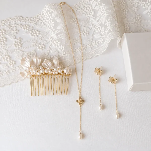 Collier EMMA forme Y 4 <p>Une petite fleur dorée au centre, une perle d'eau douce qui se balance au bout de la chaîne : EMMA est un collier perle d'eau douce en forme de Y, pensé pour le mariage. Avec les boucles d'oreilles EMMA, il forme une parure lumineuse.</p><ul><li>Fait main au Pays basque, en France</li><li>Perle d'eau douce, fleur en cuivre doré à l'or fin, chaîne en gold filled 14k</li><li>Collier de 42 cm, pendant de 6,5 cm</li></ul> Parure de mariée EMMA : collier forme Y et boucles d'oreilles à petite fleur dorée et perle d'eau douce, avec le peigne ASTRID et une dentelle, by Marguerite